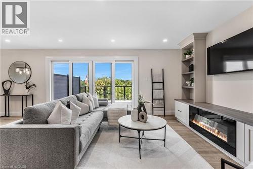 Bright living area featuring wood-finish flooring, recessed lighting, and a built-in media console with an electric fireplace - 46 Esther Avenue, Cambridge, ON 