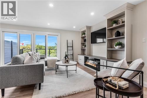 Spacious living area featuring large east facing sliding glass doors, built-in shelving, a modern electric fireplace, and recessed lighting - 46 Esther Avenue, Cambridge, ON 