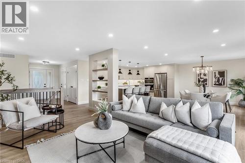 Recessed ceiling lighting, wood-finish flooring, built-in shelving, kitchen with stainless steel appliances, and a dining area with chandelier lighting - 46 Esther Avenue, Cambridge, ON 