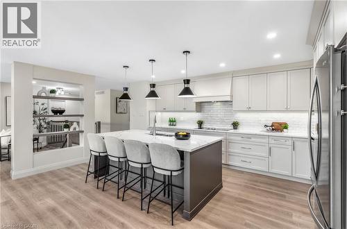 Gourmet kitchen featuring a large central island, light-finish cabinetry, stainless steel appliances, subway tile backsplash, and wood-finish flooring - 46 Esther Avenue, Cambridge, ON 