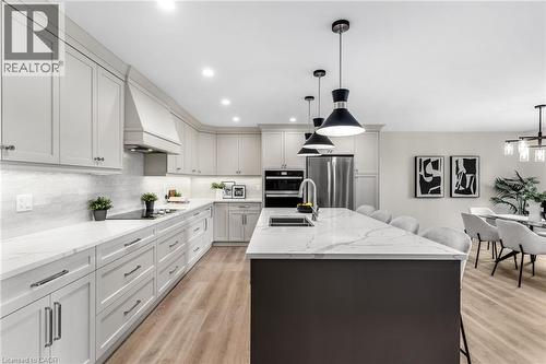 Light-toned cabinetry with a built-in range hood, white subway tile backsplash, and integrated stainless steel appliances - 46 Esther Avenue, Cambridge, ON 
