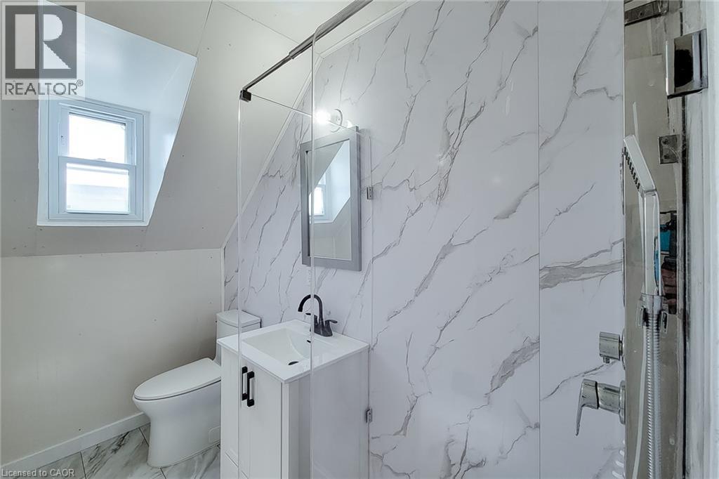 Bathroom featuring a single-handle faucet, integrated sink, mirrored medicine cabinet, and glass shower enclosure - 78 Hillyard Street, Hamilton, ON