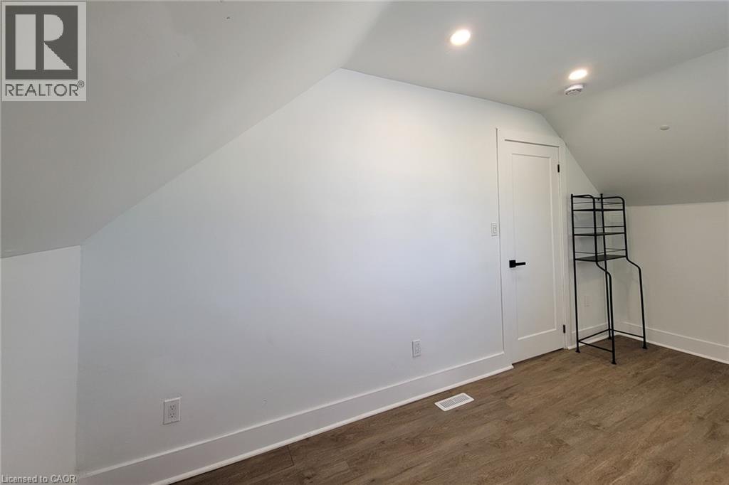 Wood-finish flooring with white baseboards, a white interior door with black hardware, and recessed ceiling lighting - 78 Hillyard Street, Hamilton, ON