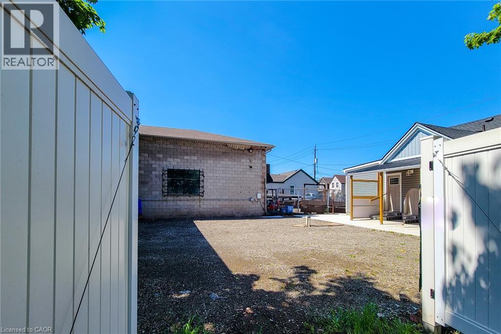 Gravel lot with perimeter fencing and a concrete block exterior building - 78 Hillyard Street, Hamilton, ON