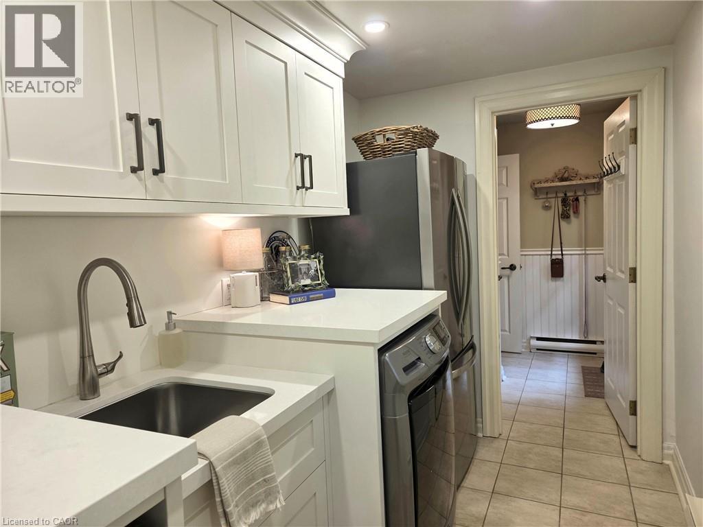 Laundry with Gravelle cabinetry, quartz countertop, Kohler goose neck tapset. Washer, dryer, stainless fridge. Pot lighting. Adjoins mudroom - 3040 First Street, Burlington, ON