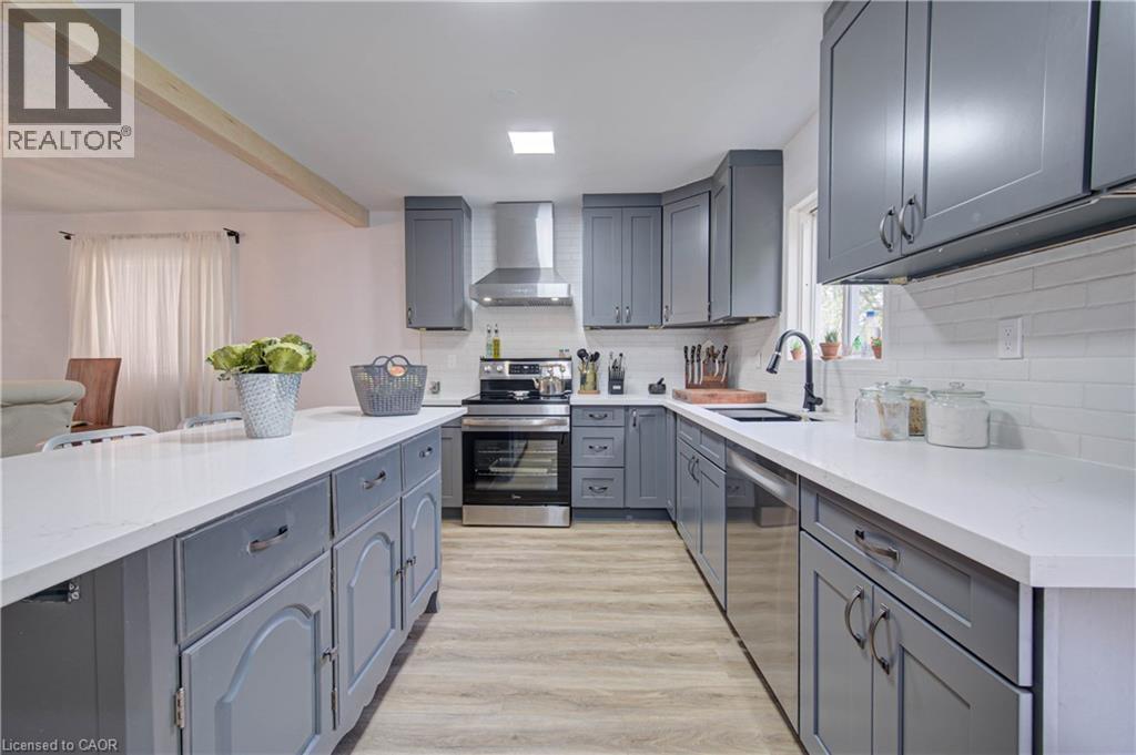 Kitchen featuring gray cabinetry, white countertops, stainless steel appliances, white subway tile backsplash, and wood-finish flooring - 317 Christopher Drive, Cambridge, ON