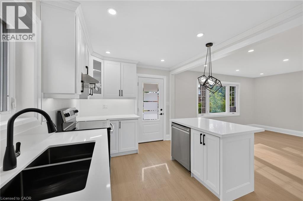 Bright kitchen featuring white cabinetry, a kitchen island with built-in dishwasher, and recessed lighting - 50 West 4Th Street, Hamilton, ON