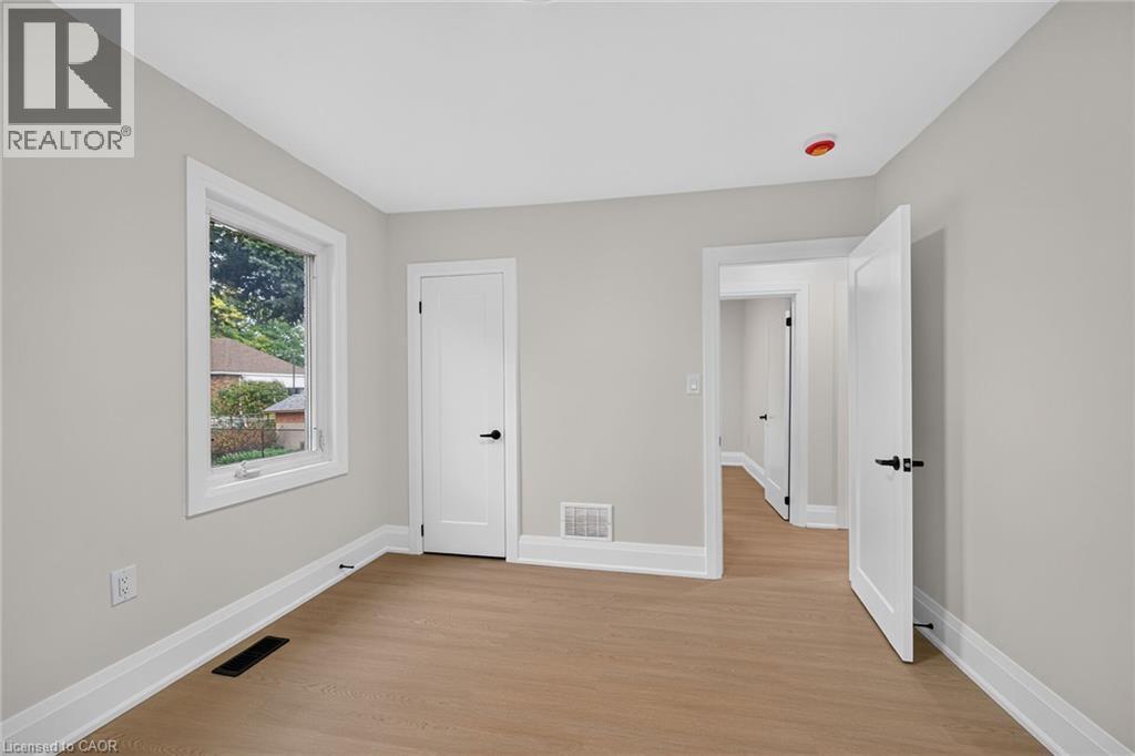 Light gray walls with white trim, wood-finish flooring, and a window with white casing - 50 West 4Th Street, Hamilton, ON