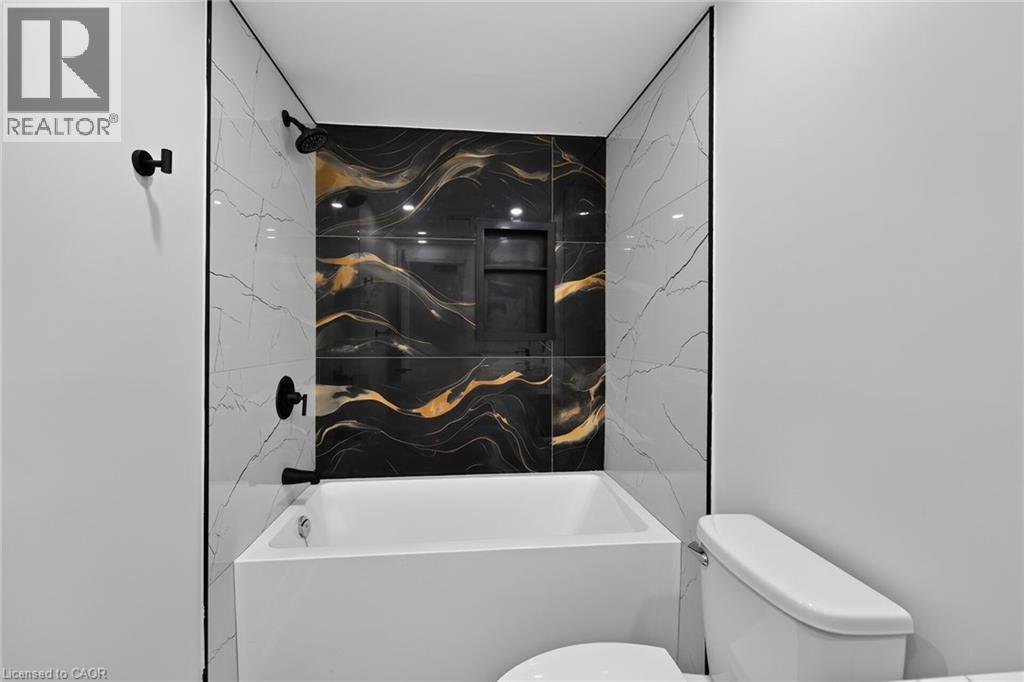White soaking tub with black and gold patterned accent tile - 50 West 4Th Street, Hamilton, ON