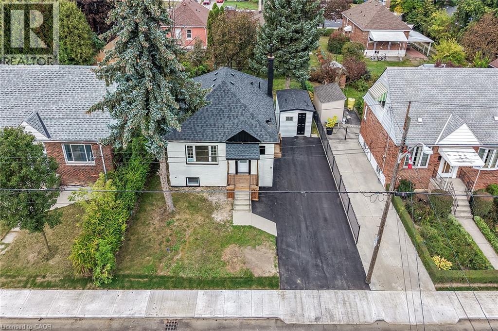 Front exterior featuring a dark asphalt driveway, white siding, and a dark shingle roof - 50 West 4Th Street, Hamilton, ON