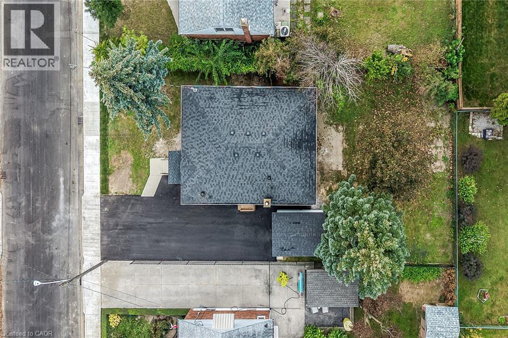Asphalt shingle roofing, paved driveway, concrete walkway, mature trees, and a grassy yard - 50 West 4Th Street, Hamilton, ON