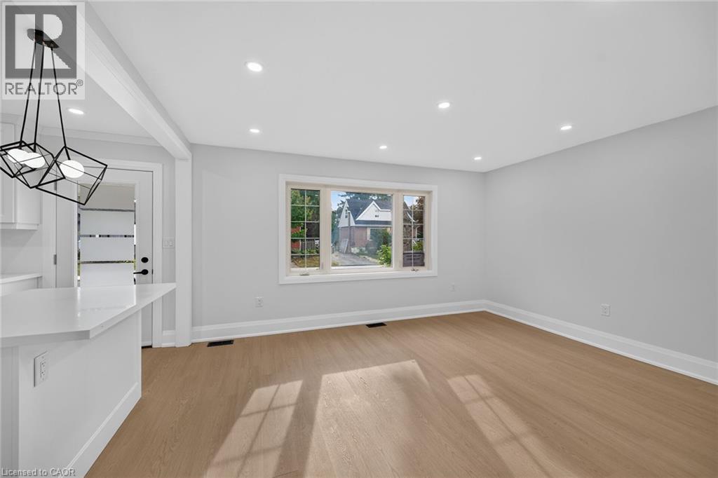 Recessed ceiling lighting, wood-finish flooring, white trim, a large window, and a modern pendant light fixture - 50 West 4Th Street, Hamilton, ON