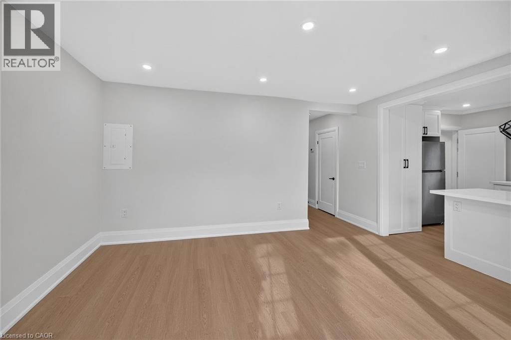 Bright, open living space featuring recessed ceiling lighting, pristine white walls, and warm wood-finish flooring throughout - 50 West 4Th Street, Hamilton, ON