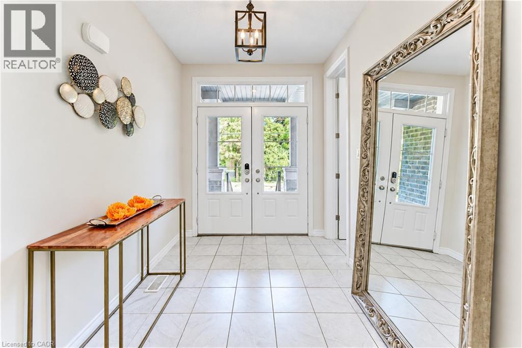 Entryway featuring twin paneled doors with transom windows, a grid-patterned ceiling light fixture, and large square tile flooring - 365 Woolwich Street, Waterloo, ON