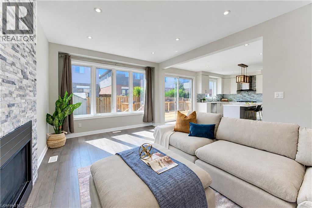 Open-concept living area featuring a stone accent wall, recessed lighting, wood-finish flooring, and expansive windows - 365 Woolwich Street, Waterloo, ON