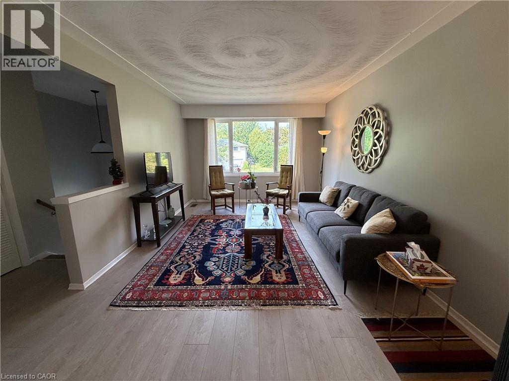 Light wood-finish flooring, a broad front window, and a half-wall partition with a handrail - 281 Toll Gate Boulevard, Waterloo, ON