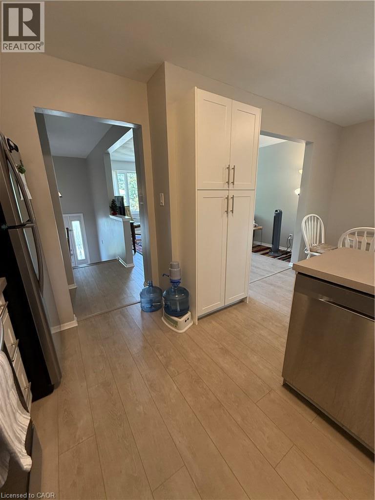 Wood-finish flooring throughout, white shaker-style cabinetry with brushed nickel hardware, and a stainless steel dishwasher - 281 Toll Gate Boulevard, Waterloo, ON