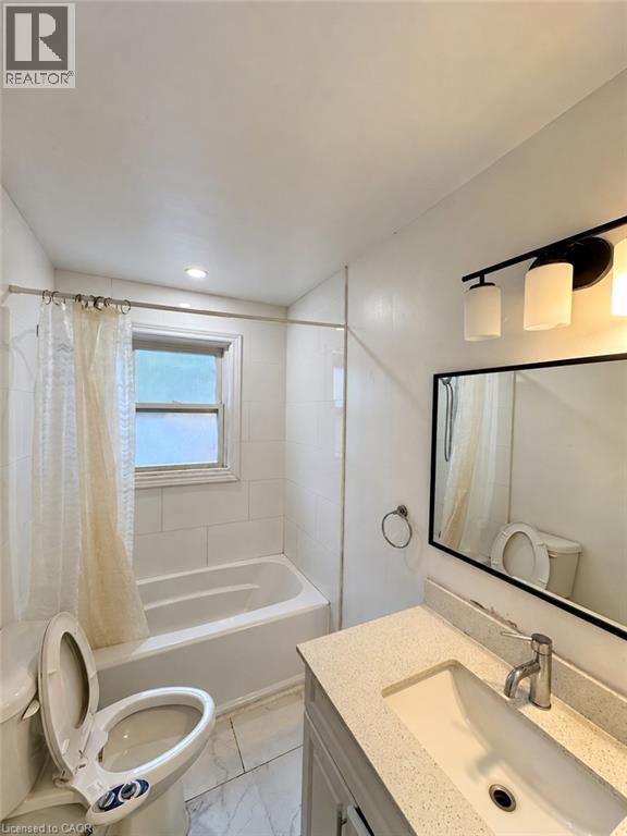 Bathroom with a white bathtub, tiled shower surround, recessed lighting, and a vanity with an integrated sink and light-toned countertop - 84 Weber Street S, Waterloo, ON