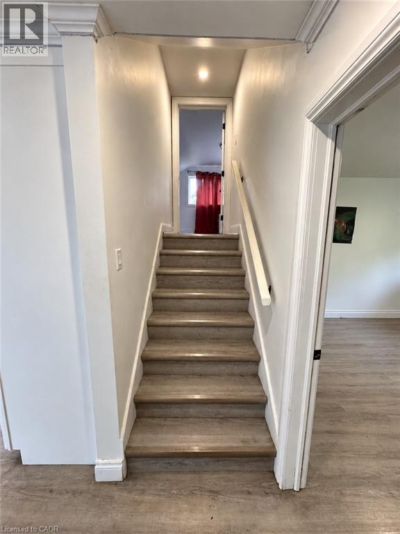 Staircase featuring wood-finish treads and risers, white painted handrail, recessed ceiling lighting, and crown molding - 84 Weber Street S, Waterloo, ON