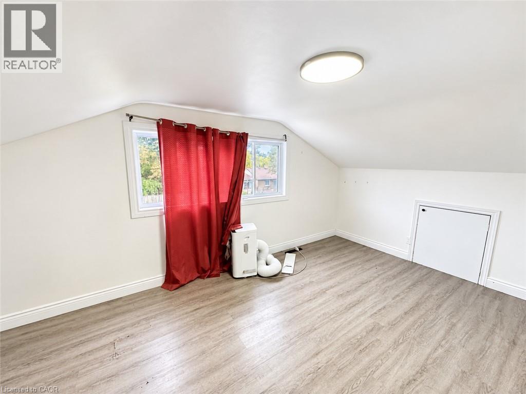 Sloped ceiling room featuring wood-finish flooring, a single window, and a built-in access panel - 84 Weber Street S, Waterloo, ON