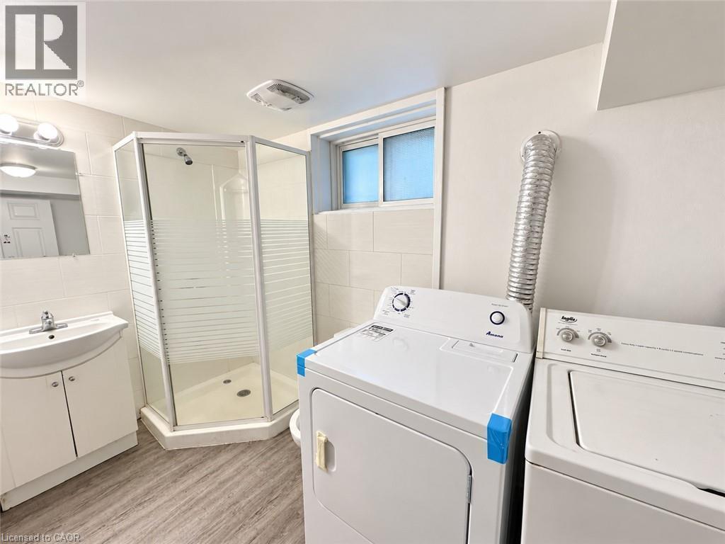Walk-in shower with frosted glass, single vanity with integrated sink, wood-finish flooring, and a compact window - 84 Weber Street S, Waterloo, ON