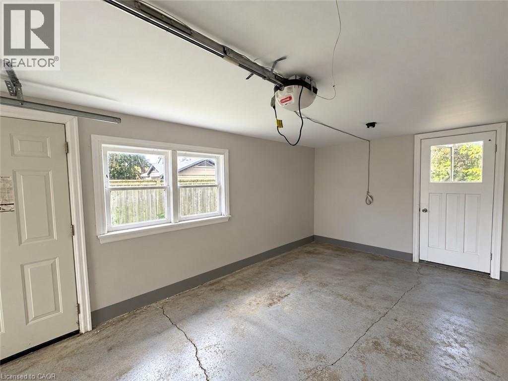 Attached garage featuring a concrete floor, painted walls, an overhead garage door opener, and a panel door - 84 Weber Street S, Waterloo, ON
