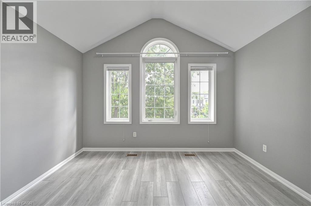 Vaulted ceiling, arched window, two vertical windows, light gray walls, and wood-finish flooring - 103 Blackbird Circle, Cambridge, ON