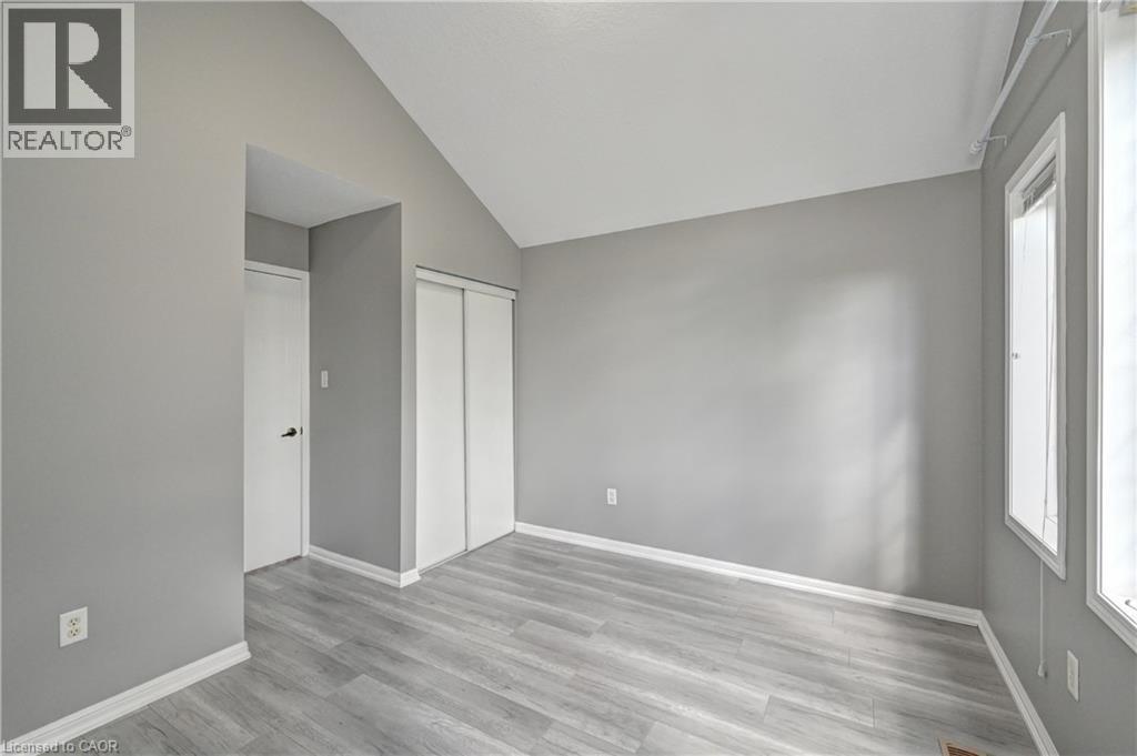 Vaulted ceiling, light wood-finish flooring, white trim, sliding closet doors, and multiple windows - 103 Blackbird Circle, Cambridge, ON