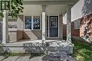 Brick and siding exterior featuring a covered porch, white-framed windows, and a panel-style entry door with divided lites - 103 Blackbird Circle, Cambridge, ON 