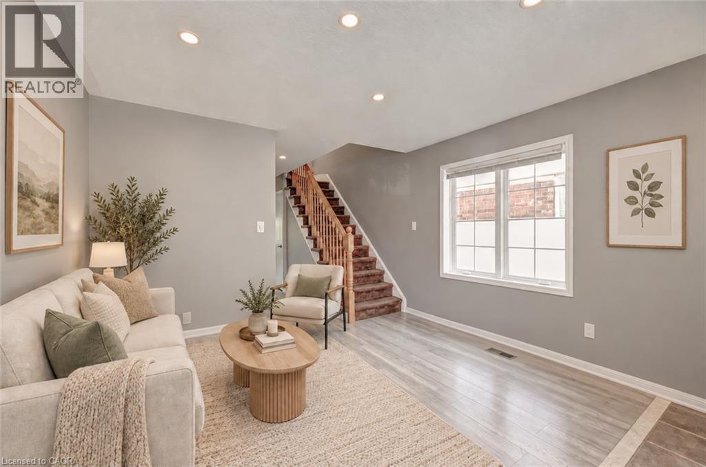 Recessed ceiling lighting, wood-finish flooring, staircase with wood banister and carpeted treads, and a multi-pane window - 103 Blackbird Circle, Cambridge, ON