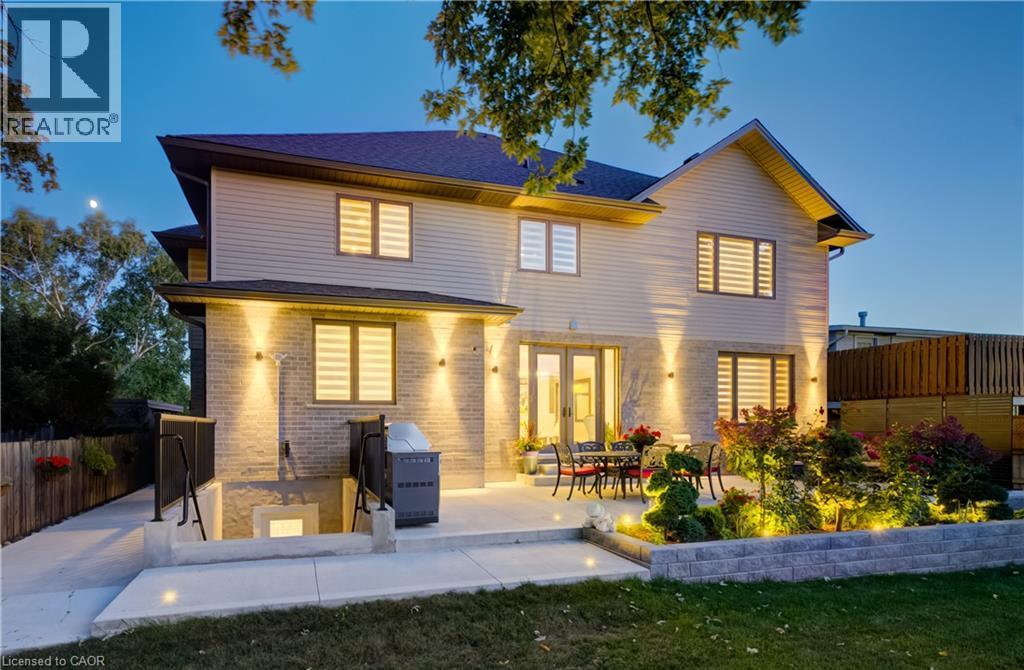 Night lighting at the rear of the house and patio. Lovely landscaping! - 61 Schweitzer Street, Kitchener, ON