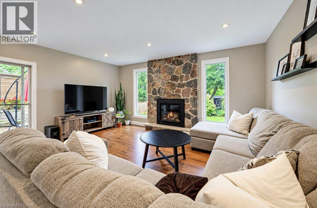 Stone-faced fireplace, recessed ceiling lighting, wood-finish flooring, and a sliding glass door to the exterior - 37 Margaret Avenue N, Waterloo, ON