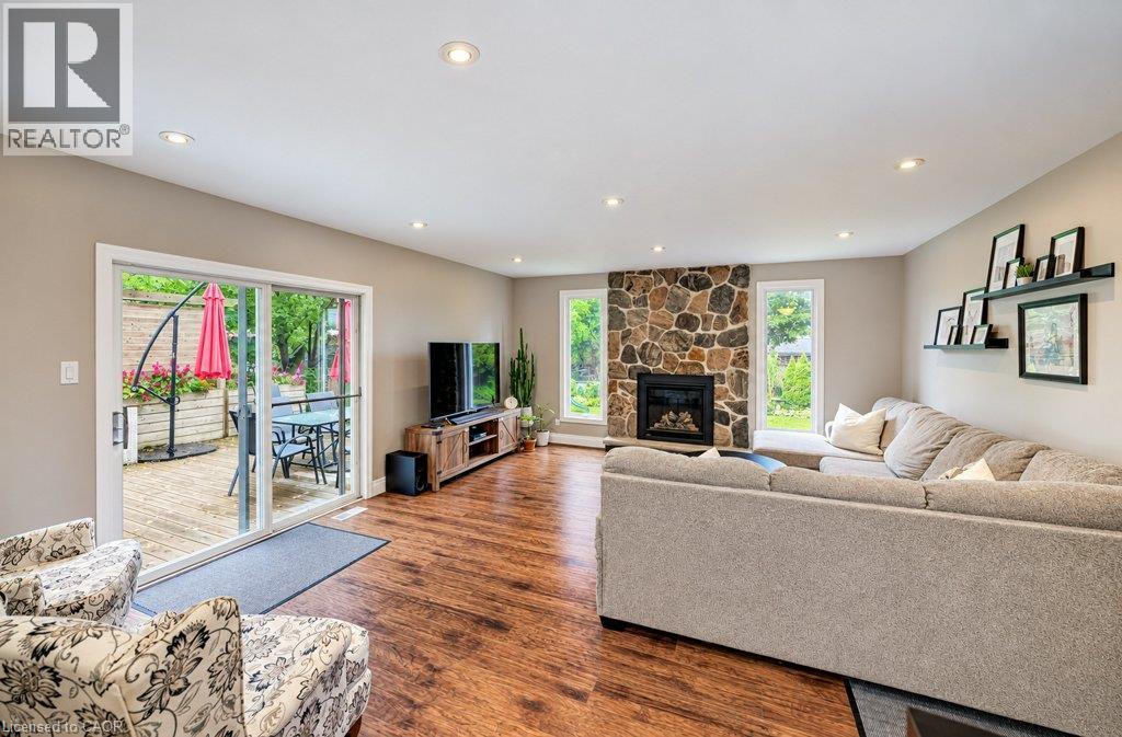 Wood-finish flooring throughout, featuring a stone-faced fireplace, recessed lighting, and white trim windows - 37 Margaret Avenue N, Waterloo, ON