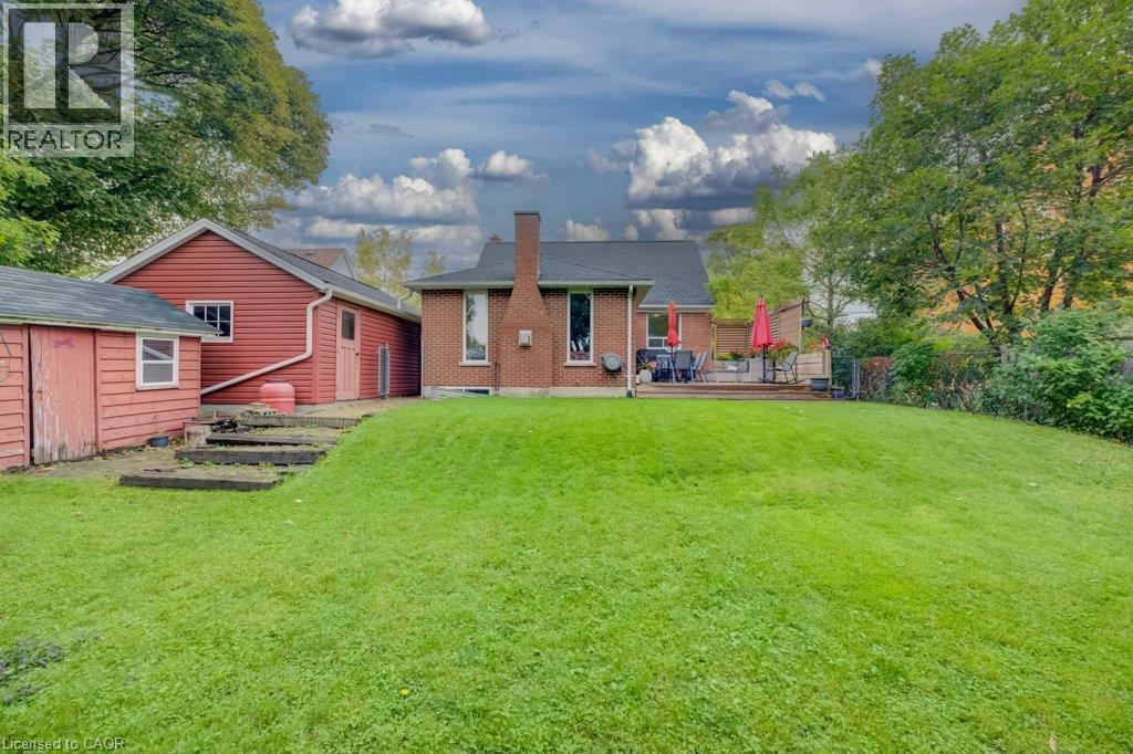 Expansive green lawn with a brick exterior home, featuring a large outdoor deck - 37 Margaret Avenue N, Waterloo, ON