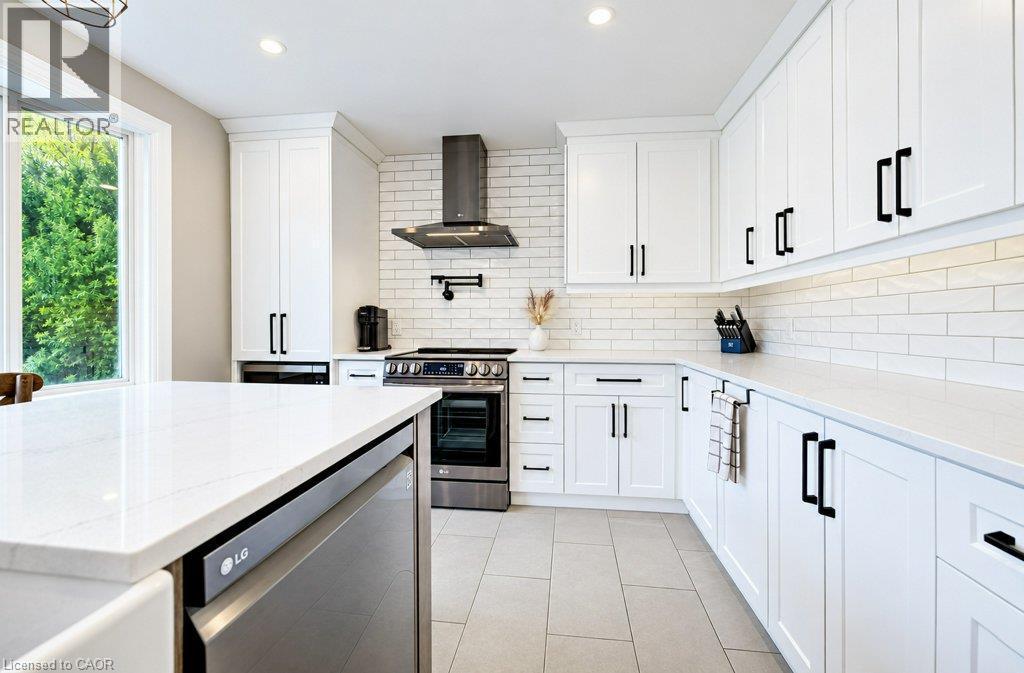 White shaker-style cabinetry with matte black hardware, light-toned countertops, subway tile backsplash, stainless steel appliances, and large format floor tile - 37 Margaret Avenue N, Waterloo, ON