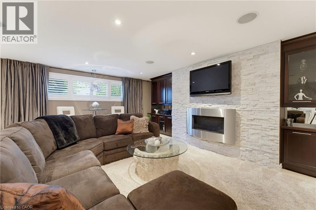 Recreation room with fireplace, TV and wall units flanking both sides. - 77 Yellow Birch Drive, Kitchener, ON