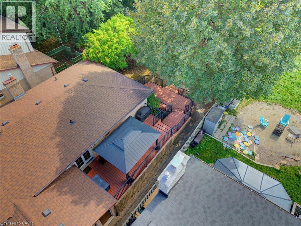 Aerial view at side of home, Multi-tier composite deck with black railings, covered gazebo area, and mature trees - 77 Yellow Birch Drive, Kitchener, ON