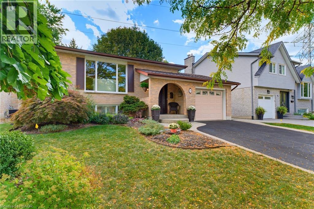 Brick exterior with an arched entryway, attached garage, and paved driveway - 77 Yellow Birch Drive, Kitchener, ON