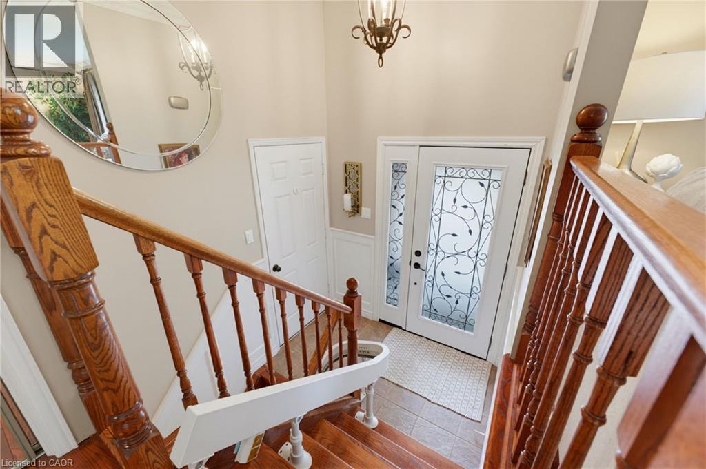 Wood-finish staircase with turned balusters, front door with transom window. - 77 Yellow Birch Drive, Kitchener, ON