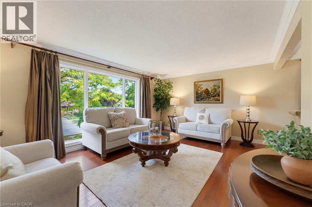 Living area featuring hardwood flooring, a large picture window, crown molding, and neutral wall tones - 77 Yellow Birch Drive, Kitchener, ON
