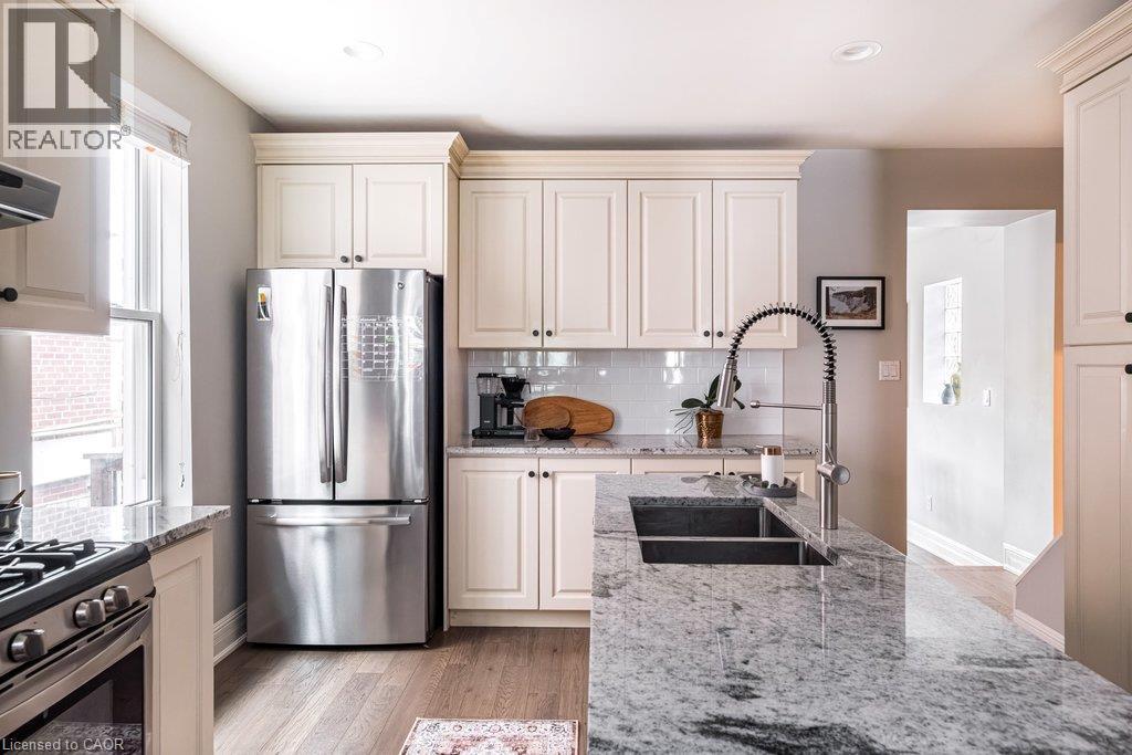 The eat-in kitchen is complemented by a bright dining room/home office combination, featuring a cozy fireplace and walkout to the large deck and beautifully landscaped backyard. - 132 Herkimer Street, Hamilton, ON