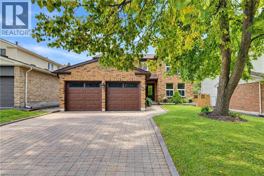 Brick exterior with a double garage featuring two brown panel doors - 104 Deerwood Crescent, Kitchener, ON