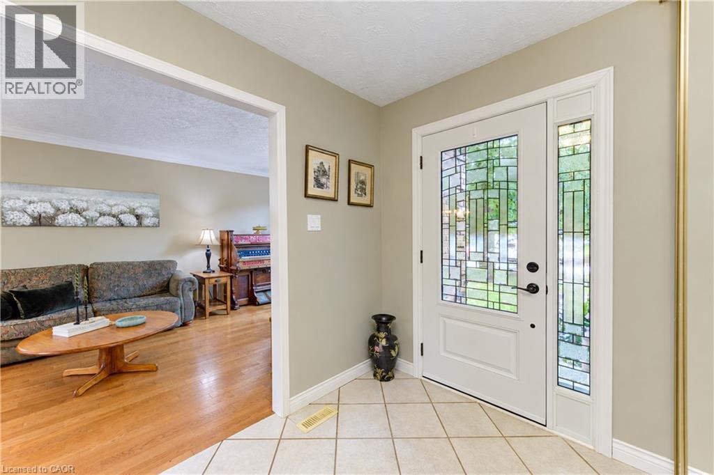 White paneled front door with decorative glass inserts, side-light window with decorative glass, and a black handle set - 104 Deerwood Crescent, Kitchener, ON