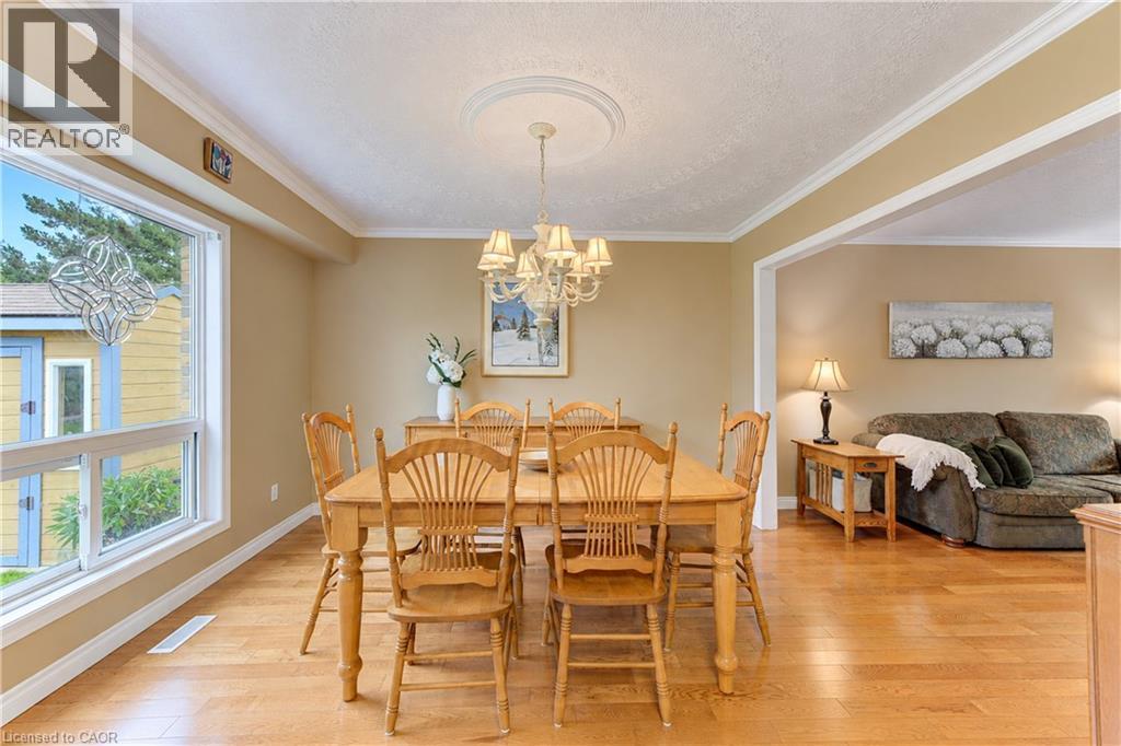 Hardwood flooring, crown molding, white trim, recessed archway, and a decorative ceiling medallion with a chandelier - 104 Deerwood Crescent, Kitchener, ON