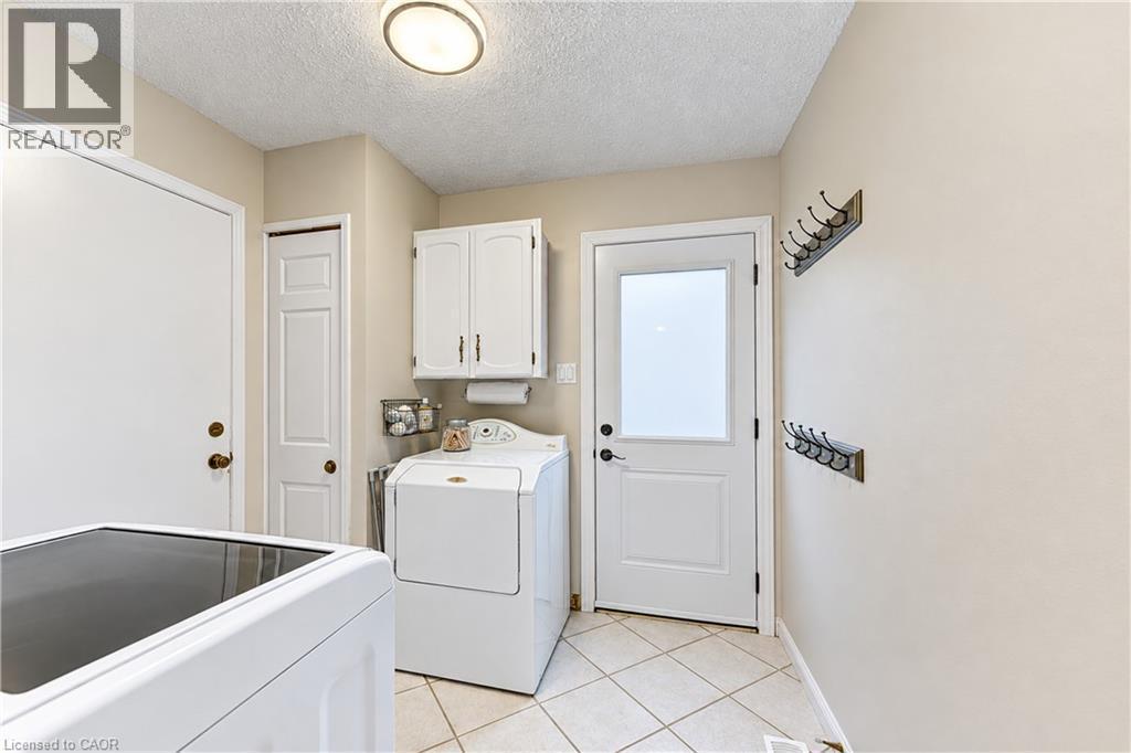 White upper cabinetry, tiled flooring, and a frosted pane door - 104 Deerwood Crescent, Kitchener, ON