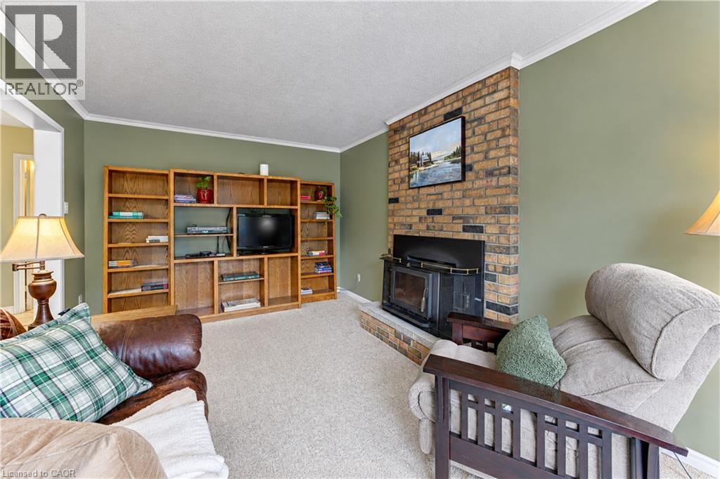 Brick-clad fireplace with a hearth, integrated wood-burning insert, and a large built-in media center with shelving - 104 Deerwood Crescent, Kitchener, ON