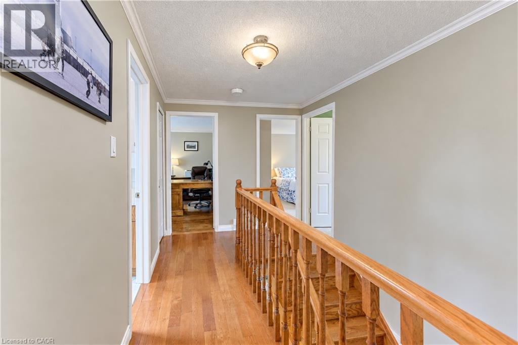 Hardwood flooring, light wood-finish stair railing, crown molding, and flush mount ceiling light fixture - 104 Deerwood Crescent, Kitchener, ON