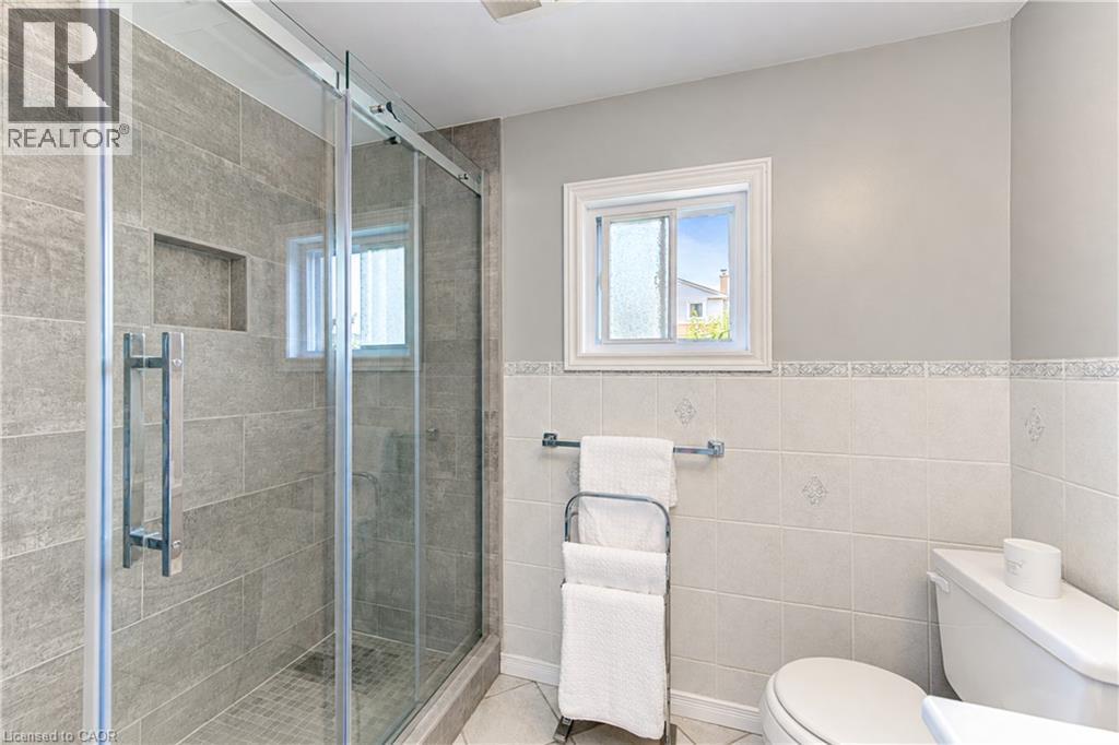 Glass-enclosed shower with gray tiled walls and a built-in niche - 104 Deerwood Crescent, Kitchener, ON