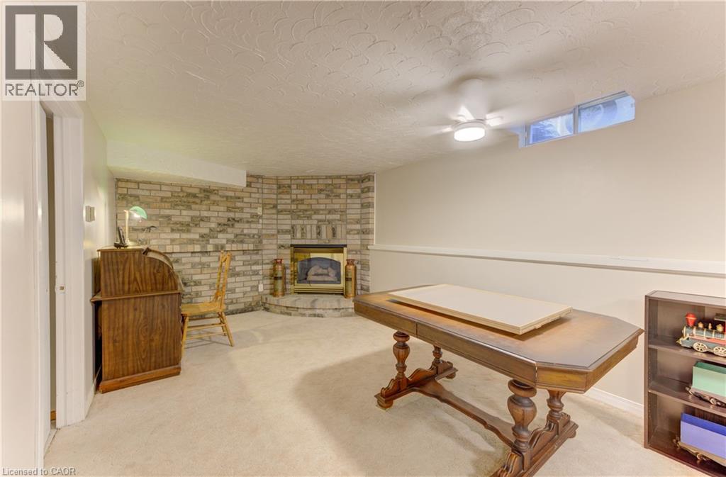 Brick accent wall with a built-in fireplace, carpeted flooring, and a ceiling-mounted light fixture - 104 Deerwood Crescent, Kitchener, ON