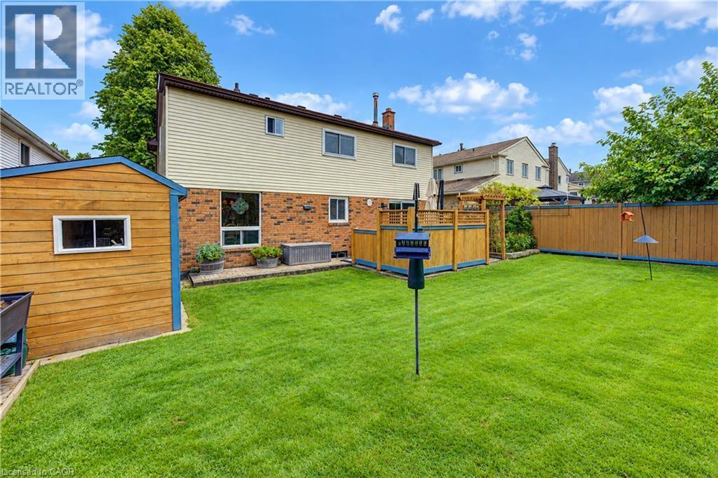Expansive lawn with a wooden shed, a privacy fence, and a patio area with a wooden railing - 104 Deerwood Crescent, Kitchener, ON